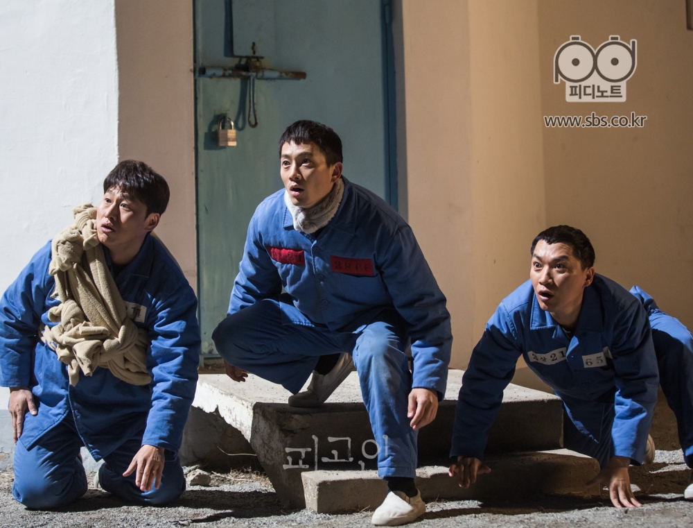 감시탑 앞에서 한껏 긴장된 표정으로 앉아 있는 오대환, 지성, 조재윤