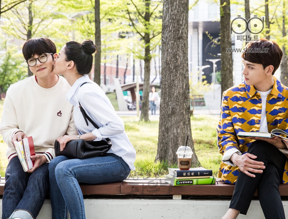 대학교 교정 안에 있는 벤치에 앉아 팔짱 끼고 있는 지욱과 유정. 지욱의 뺨에 유정이 뽀뽀를 하고 있는 상황을 옆에 앉아 지켜보고 있는 은혁