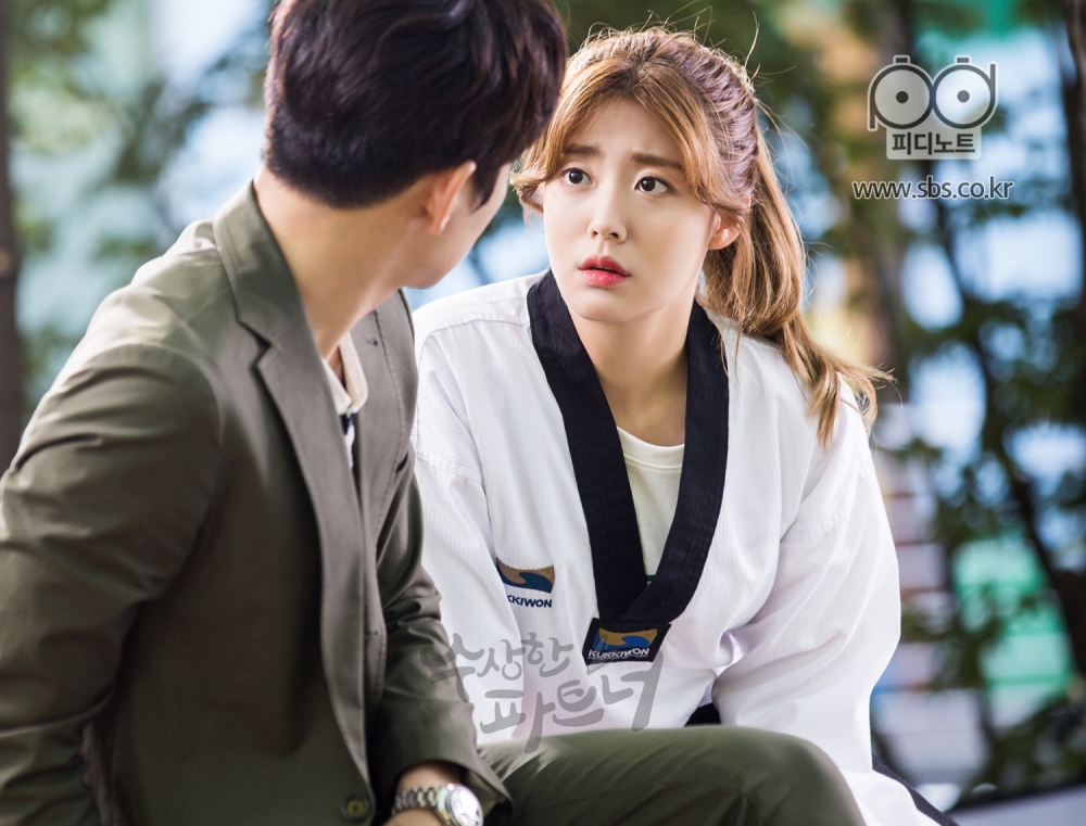 벤치에 앉은 봉희와 지욱. 봉희가 지욱에게 얼굴을 가까이 밀자 지욱이 당황하여 몸을 뒤로 뺀다.