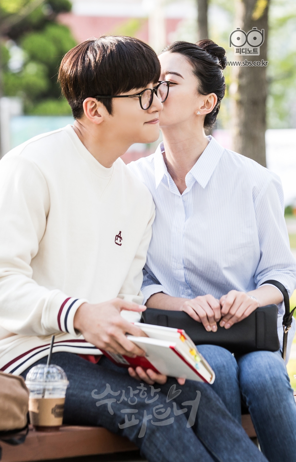 대학교 교정 안에 있는 벤치에 앉아 팔짱 끼고 있는 지욱과 유정. 지욱의 뺨에 유정이 뽀뽀를 하고 있다.